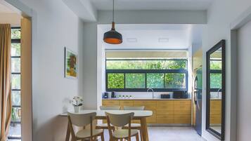 Une cuisine moderne dotée d’une grande fenêtre, de meubles en bois et d’un coin repas avec une table et des chaises.