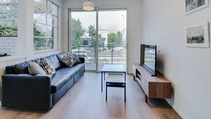 A modern living room with a sofa, a coffee table, and a TV on a stand. - Carmel Boutique (Haifa)