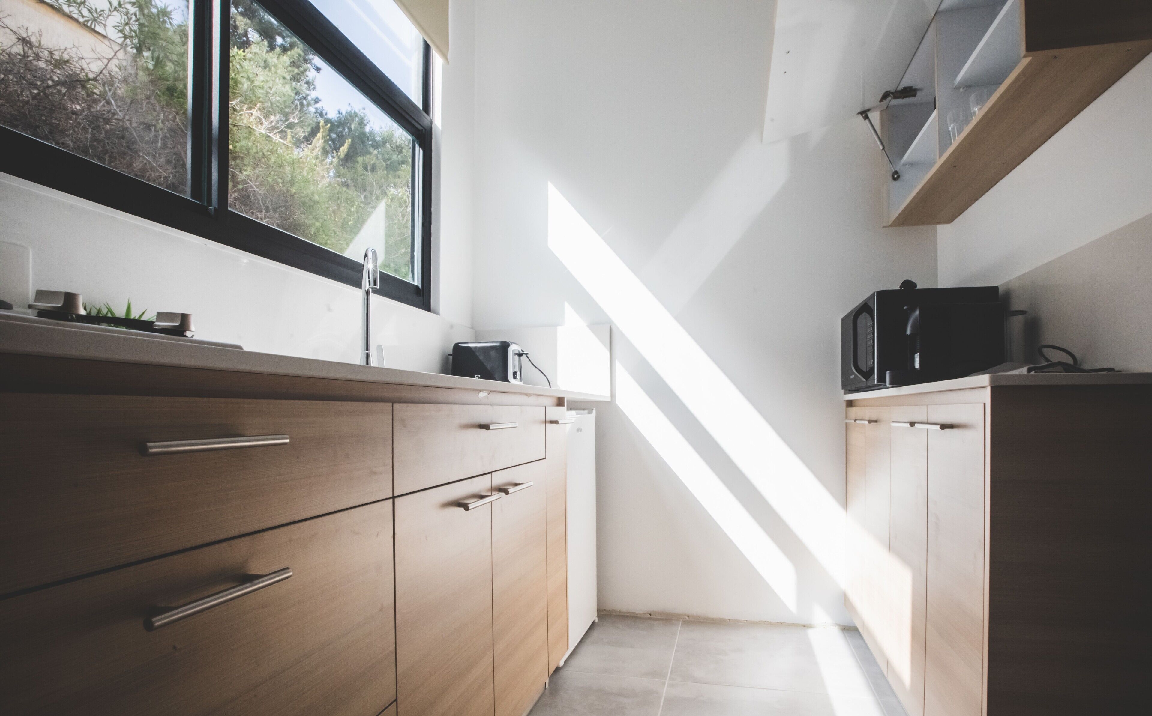 A modern kitchen with wooden cabinets, a stainless steel sink, and a window providing natural light.