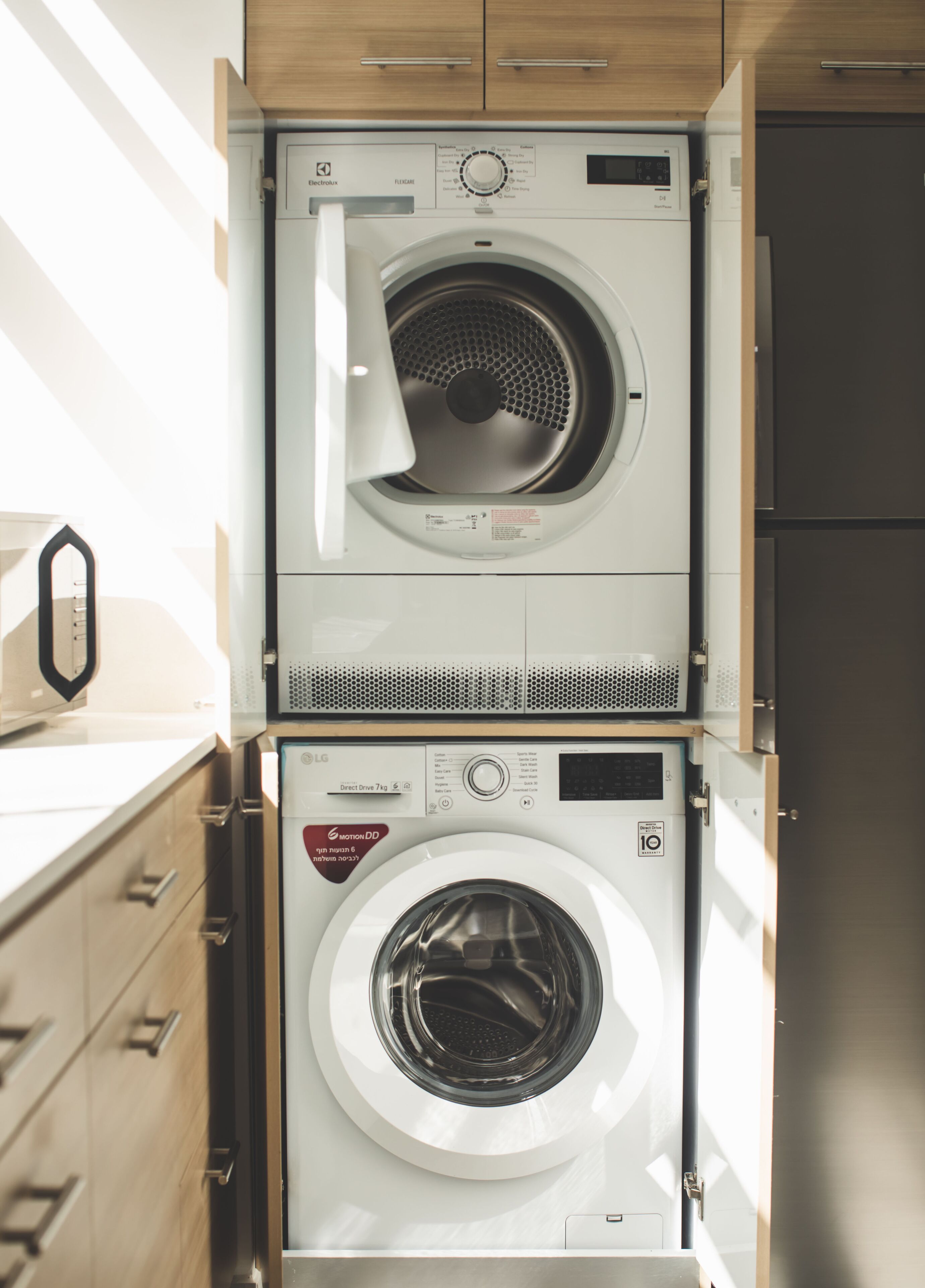 A compact, modern laundry room with two stacked front-loading washing machines.