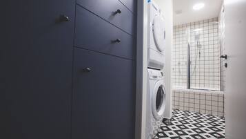 A laundry room with a washing machine, a dryer, and a tiled floor.