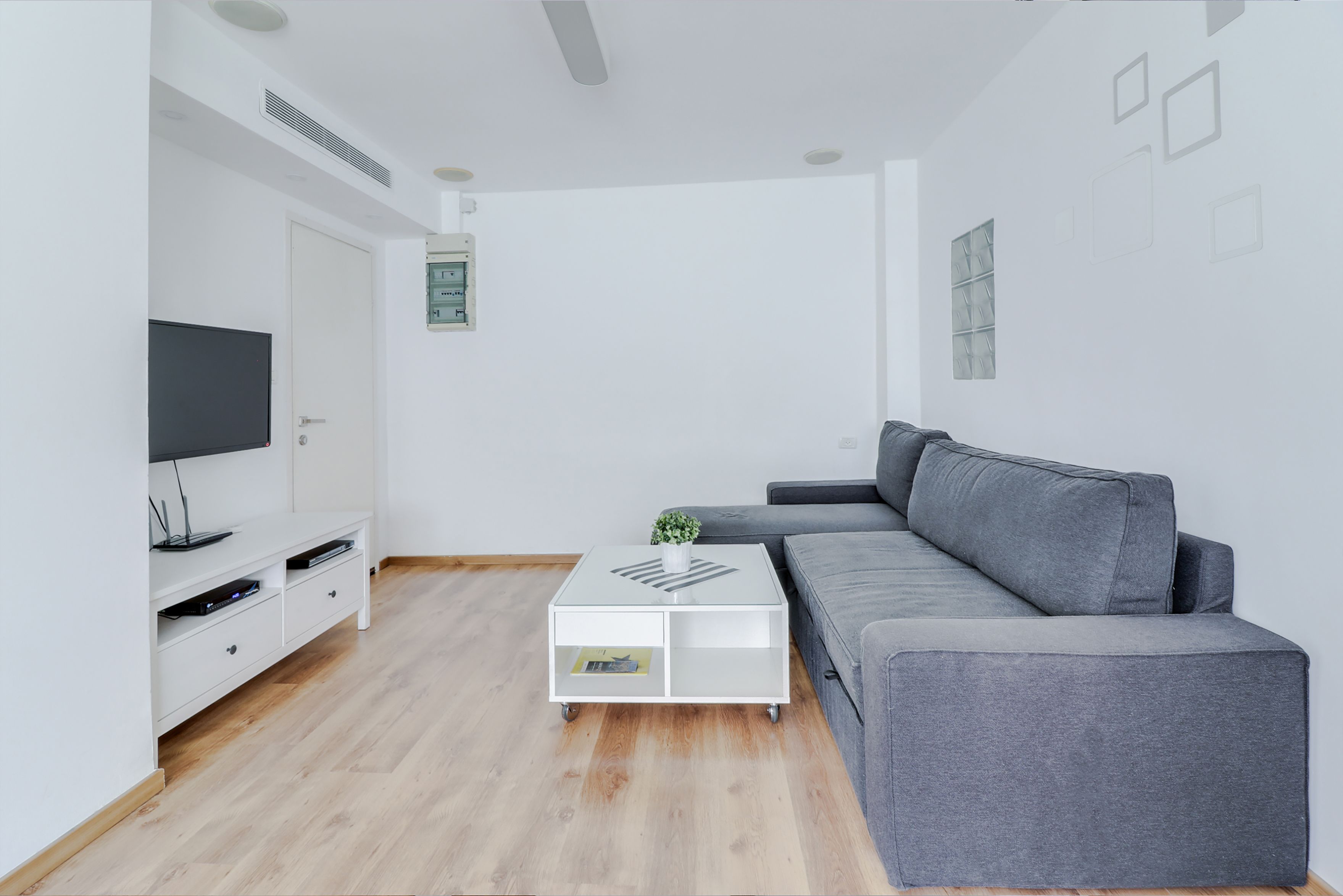 A modern living room with a grey sofa, white entertainment unit, and a coffee table.