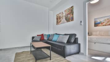 Een moderne woonkamer met een zwarte leren bank, een klein houten tafeltje en een gestreept tapijt.
