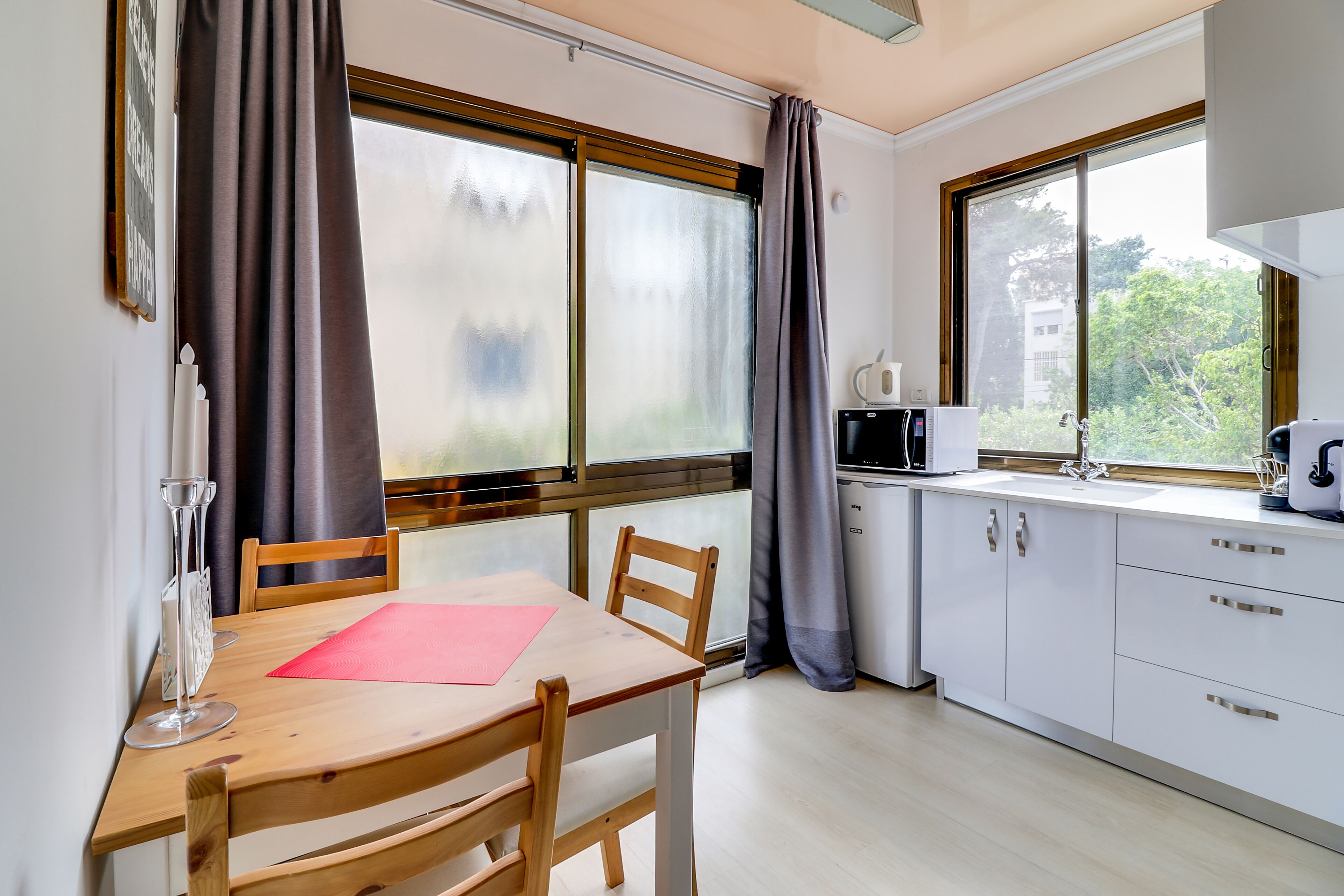 A modern kitchen with a wooden table, chairs, and a microwave.