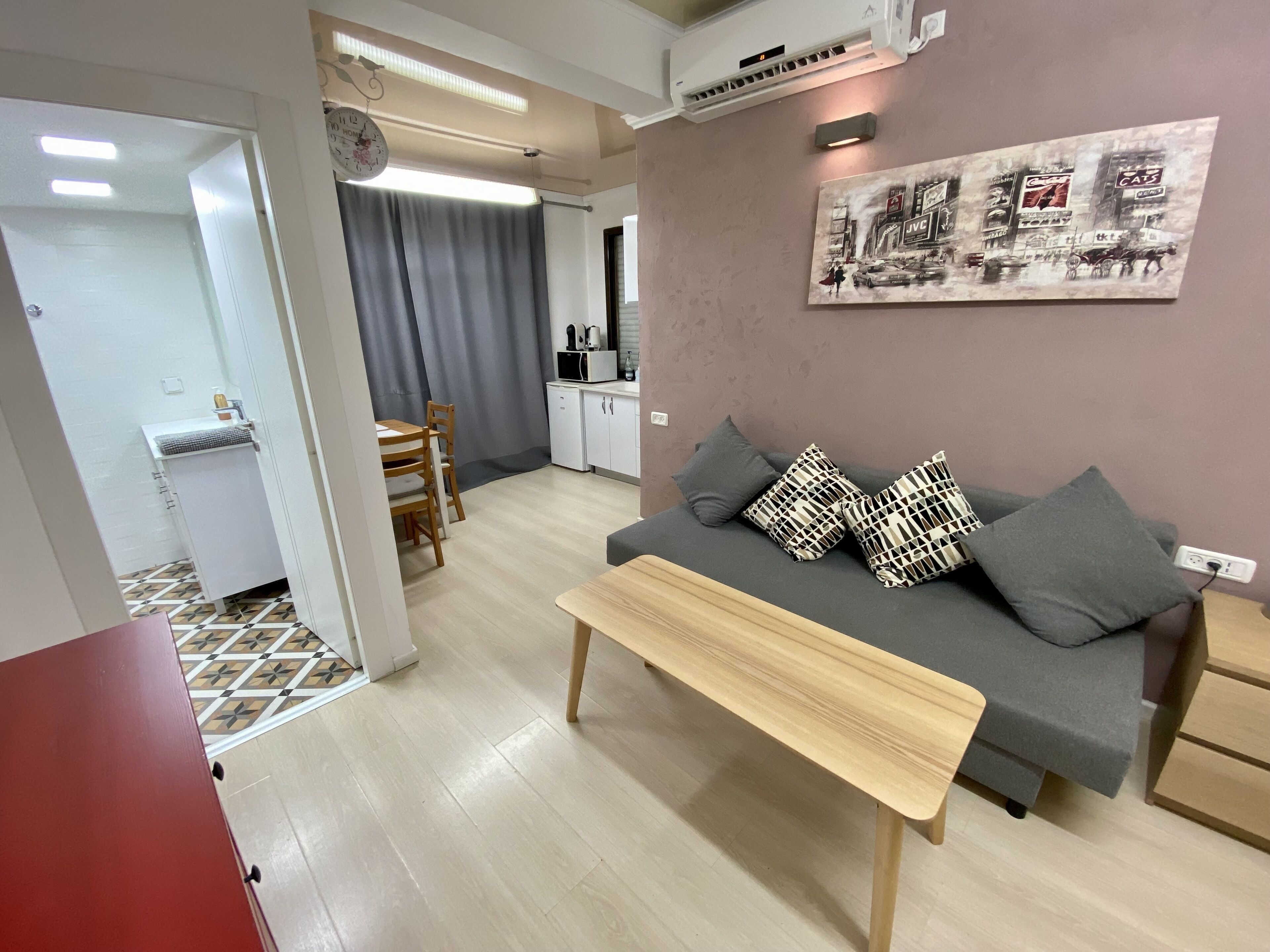 A modern living room with a sofa, a coffee table, and a dining area with a table and chairs.