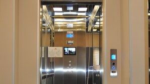 Un ascensor moderno con pantalla digital, panel de control e instrucciones de emergencia.