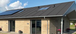 A building with a metal roof, solar panels, and a covered entrance.