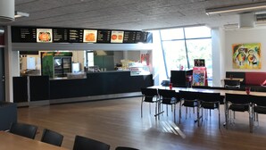 A restaurant with a menu board, seating area, and a vending machine. - Bredebro camping (Bredebro)