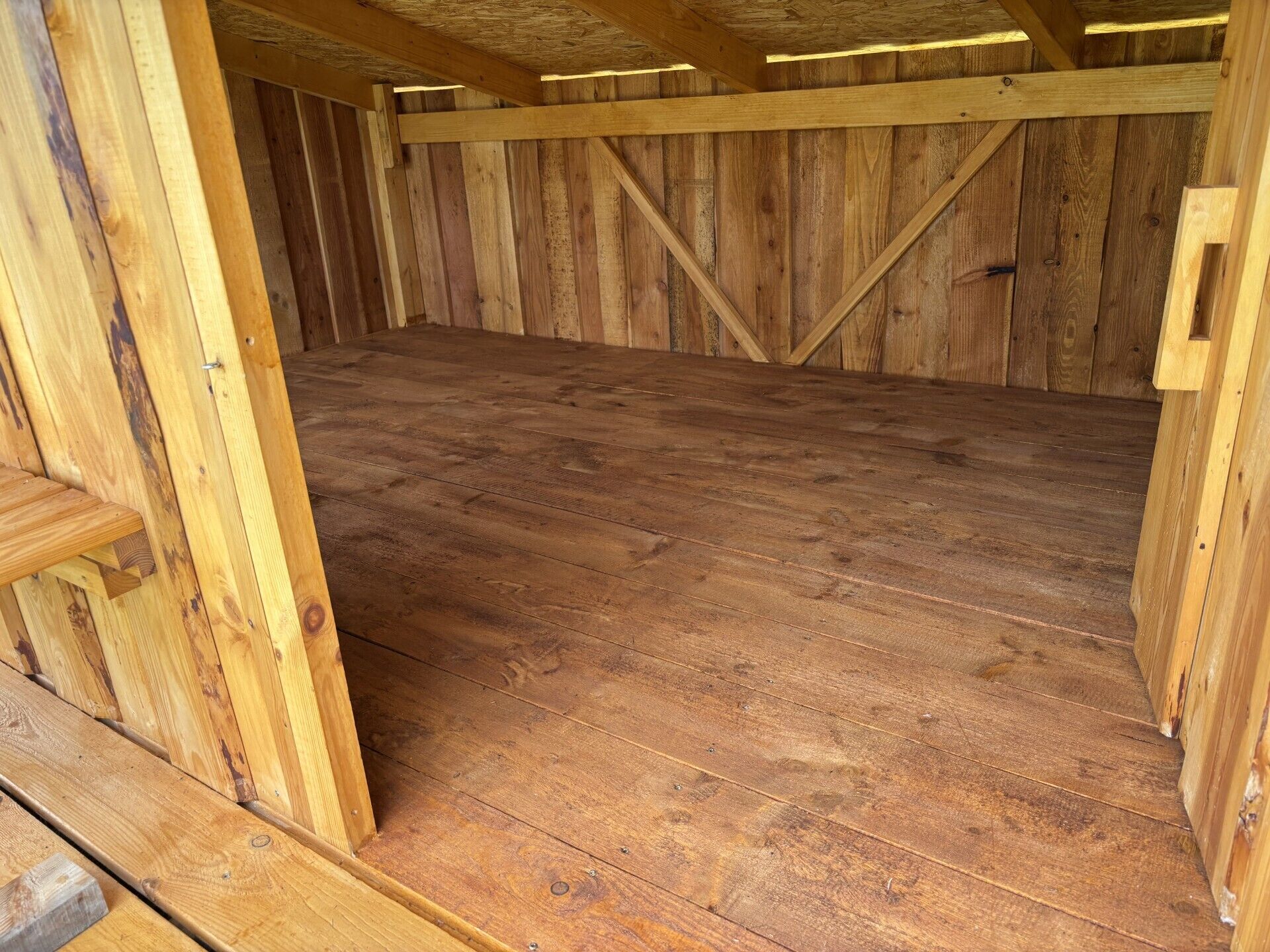A wooden interior with a sloped ceiling and a wooden floor.