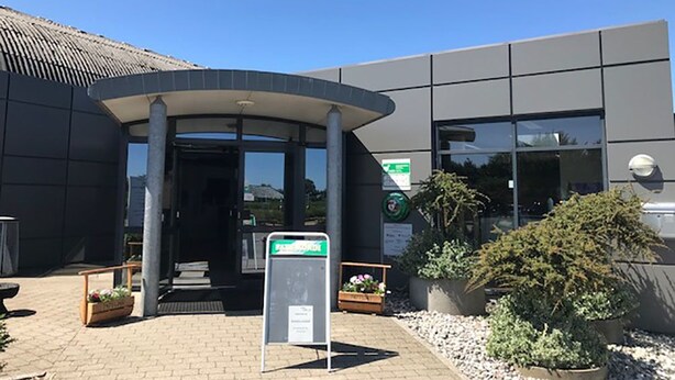 A modern building entrance with a curved canopy, a reception desk, and potted plants. - Bredebro camping (Bredebro)