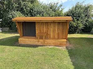 A wooden cabin with a porch, a door, and a small table.