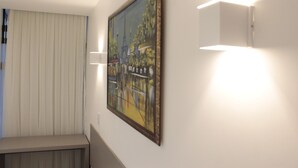 A room with a painting on the wall, a bench, and a wall-mounted light fixture. - Hotel Hellyu's (Nucleo Bandeirante)