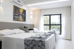 A hotel room with two beds, a painting on the wall, a window with curtains, and a bedside table with a lamp. - Hotel Hellyu's (Nucleo Bandeirante)