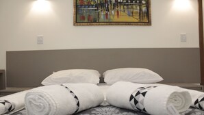 A hotel room with a bed, two white pillows, and two rolled towels with a black and white pattern. - Hotel Hellyu's (Nucleo Bandeirante)