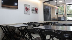 A conference room with a large table, chairs, a flat-screen TV, and artwork on the wall. - Hotel Hellyu's (Nucleo Bandeirante)