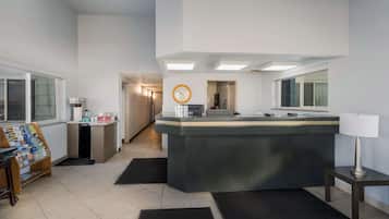 A hotel reception area with a counter, a clock, and a lamp.