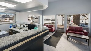 A modern reception area with a counter, seating, and large windows offering a view of the outdoors.