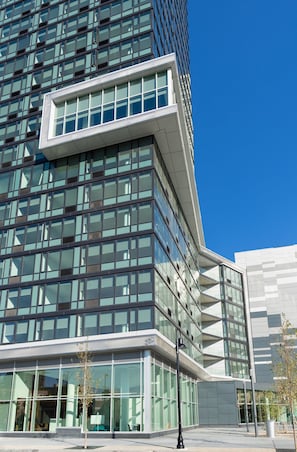 A modern building with a glass facade and a corner entrance. - Deedee's Sky Rise Apartments - Newport 2 (Jersey City)