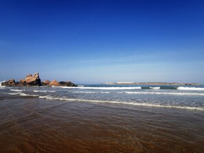 A beach with clear skies, waves, and rocky formations. - Beautiful villa with sea view, large pool, Close to golf and the beach (Essaouira)