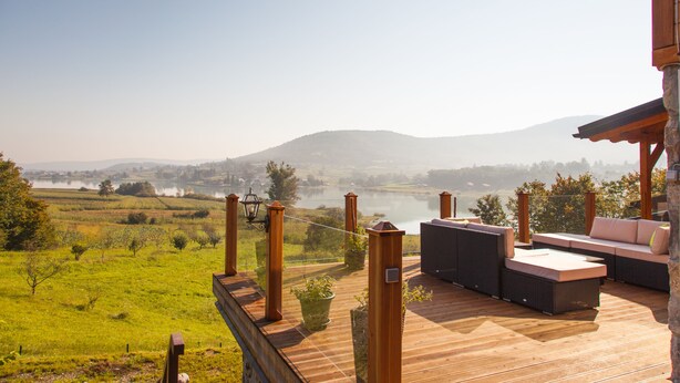 A wooden deck with outdoor seating and a view of a lake and hills. - Lakefront Villa Jelenic By Bertovic in Croatia with a squash court, gym, cinema (Ogulin)