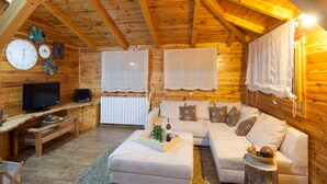 A cozy wooden cabin with a living area featuring a sofa, a television, and a dining table. - Lakefront Villa Jelenic By Bertovic in Croatia with a squash court, gym, cinema (Ogulin)
