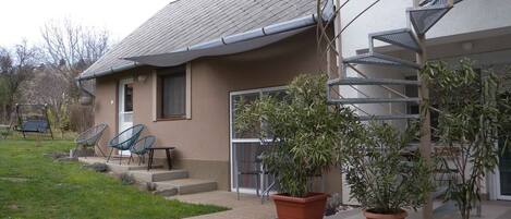 Una casa residencial con techo gris, una escalera y tres macetas con plantas en la parte frontal.