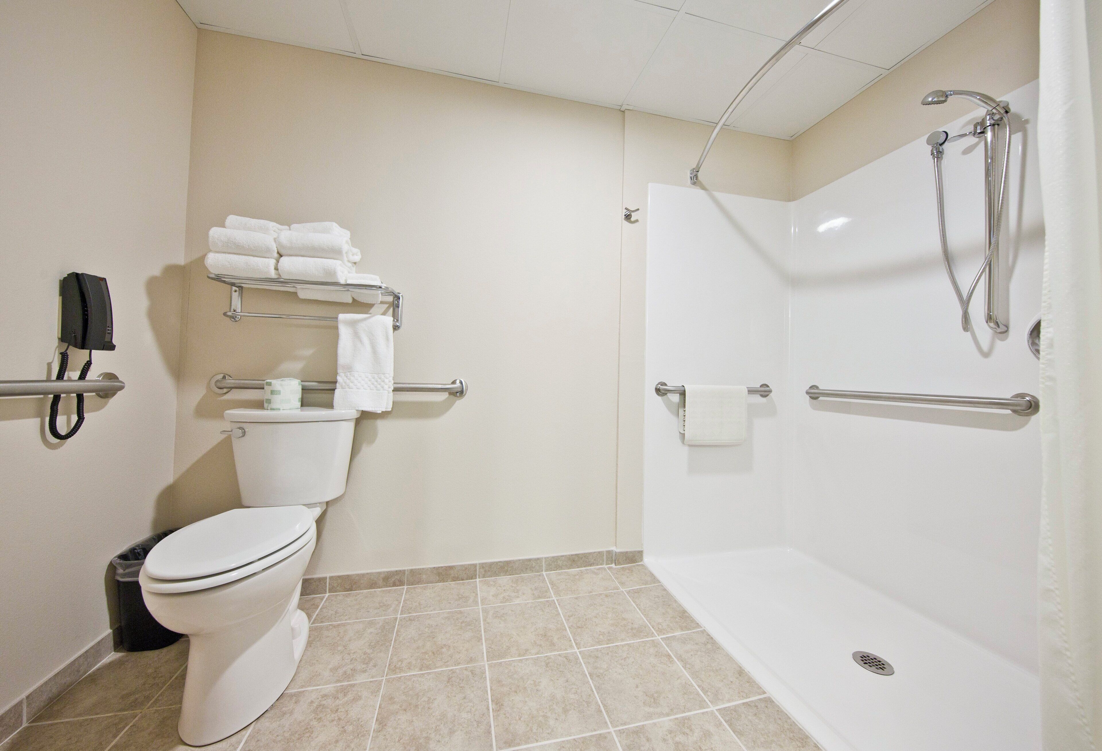 A bathroom with a toilet, a shower, and a hand dryer.