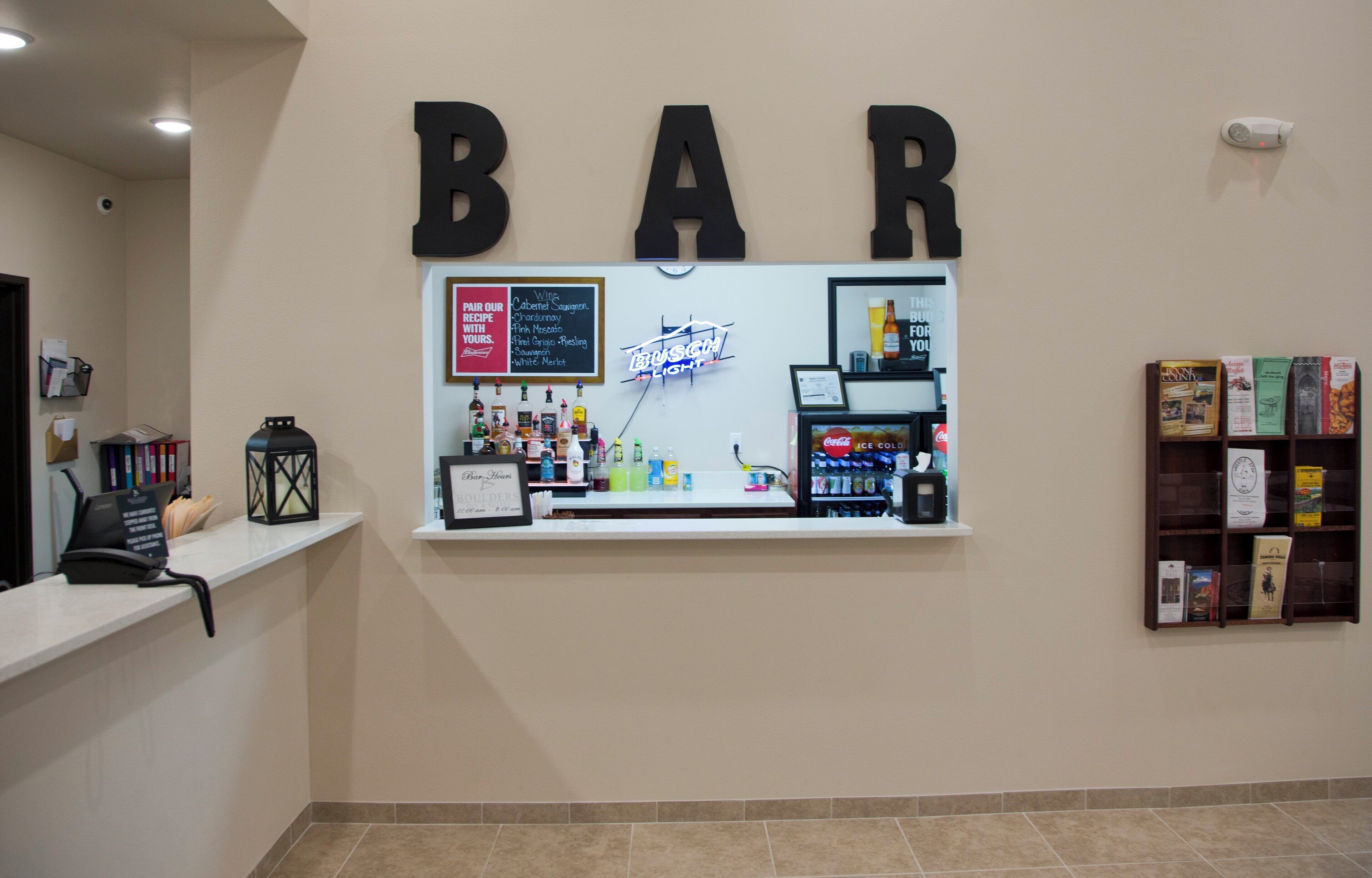 A bar area with a neon sign, a liquor display, and a bookshelf with books.