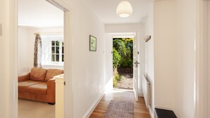A hallway with a wooden floor, a bench, a door leading outside, and a window with a view of greenery. - Horner Cottage, Luccombe (Nr Porlock)