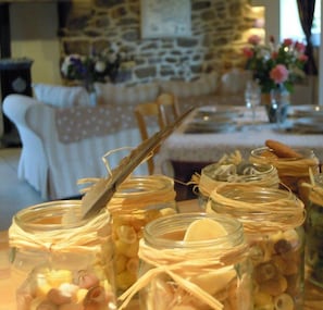 A dining table with glass jars containing various food items, tied with twine. - Stone face character house island of Batz 70m from the beach. (Santec)
