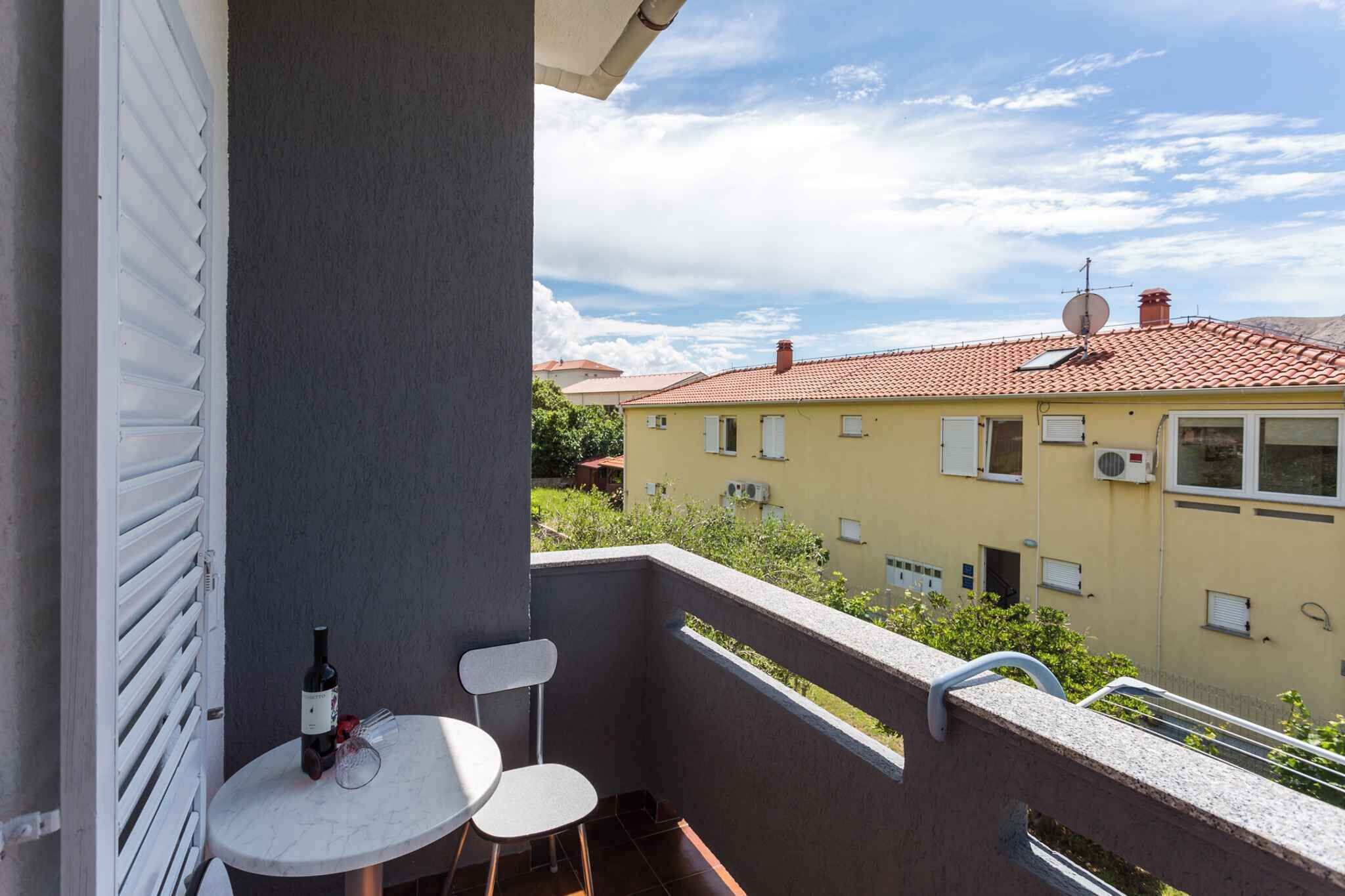 Un balcon avec une table, deux chaises et une bouteille de vin.