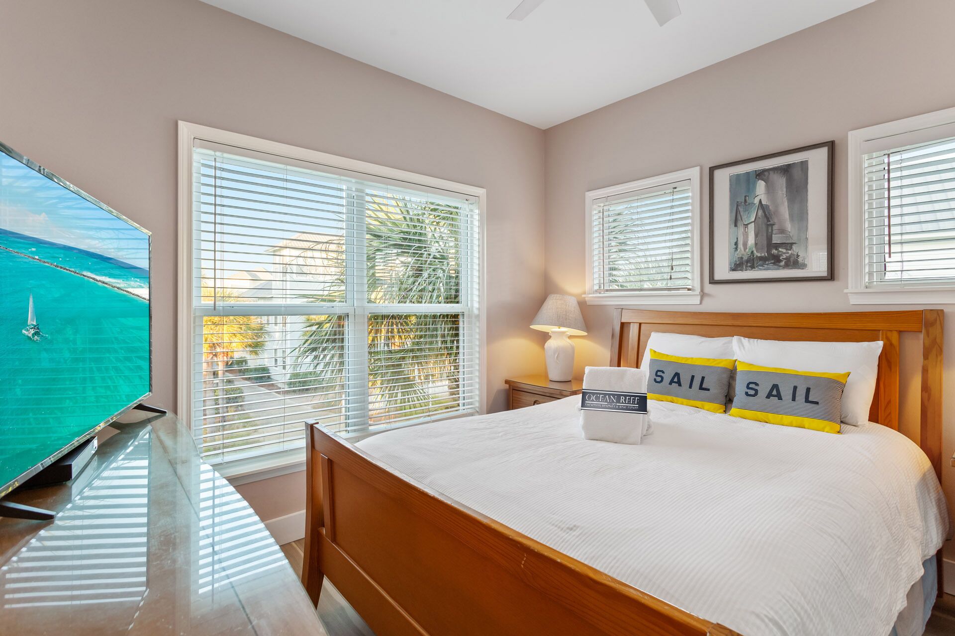 A bedroom with a bed, a TV, and a window with a view of the ocean.