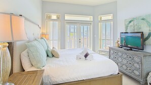 Un dormitorio con cama, cómoda, televisor y ventana con persianas.
