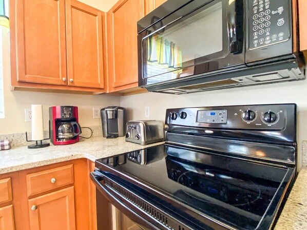 A kitchen with wooden cabinets, a microwave, a toaster, a coffee maker, and an oven.