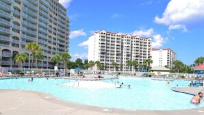 Una amplia piscina al aire libre rodeada de palmeras y edificios de hotel.