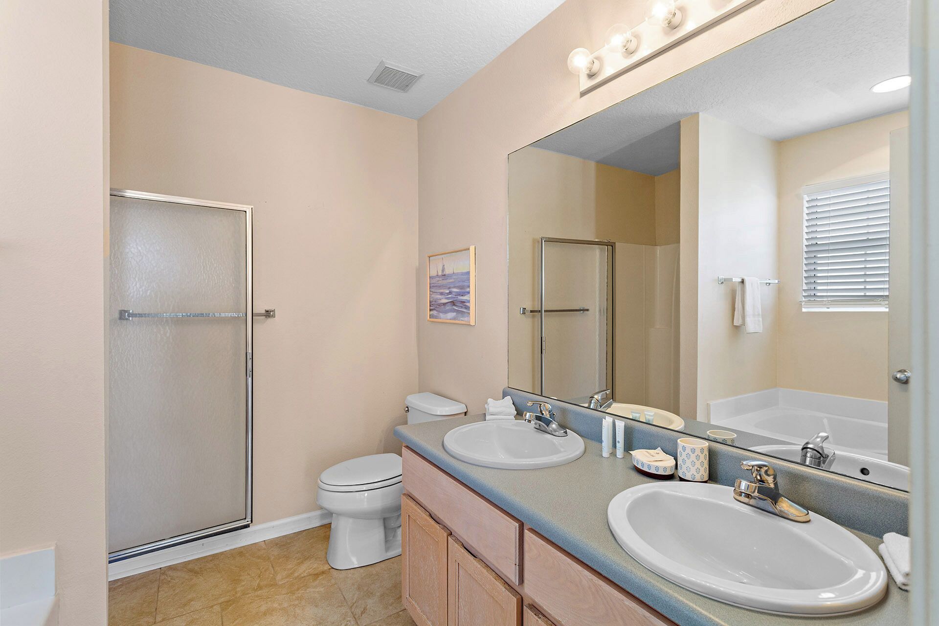 Une salle de bain avec une douche, des toilettes, deux lavabos et un grand miroir.