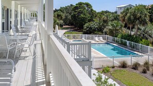 A poolside area with a rectangular pool, white railings, and outdoor seating. - Legends 310 - Santa Rosa Beach, Community Pool, Hot Tub, Tennis Courts! (Santa Rosa Beach)