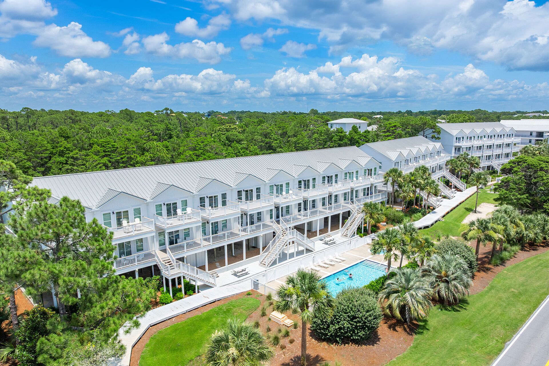 A large resort with multiple buildings, a swimming pool, and lush greenery.