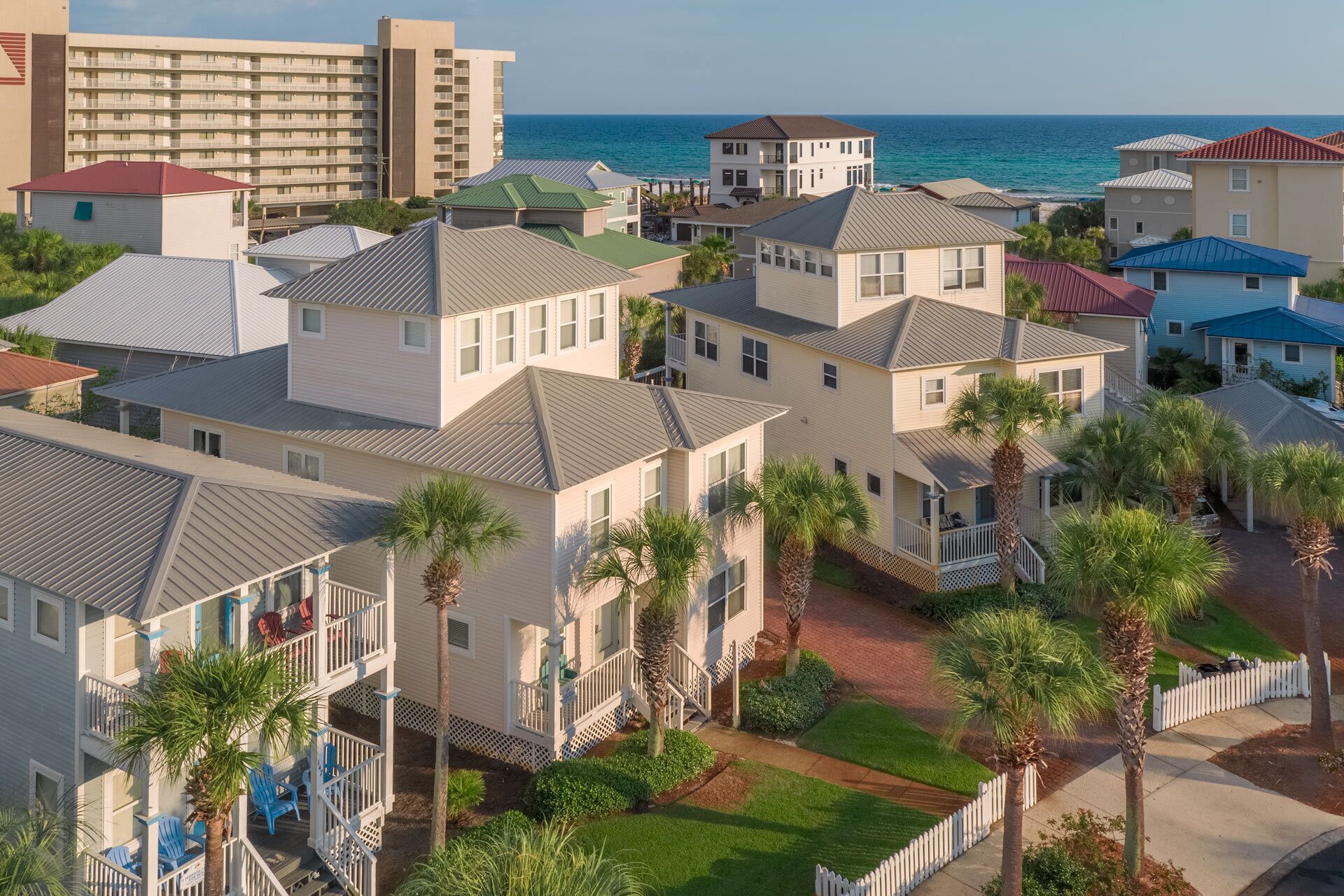 A coastal residential area with multiple two-story houses, some with balconies, and a large hotel in the background.
