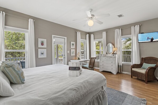 A bedroom with a bed, a dresser, a chair, a ceiling fan, and a window with curtains.