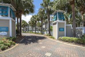A pathway leading to Gulfside Cottages with a white fence and palm trees.