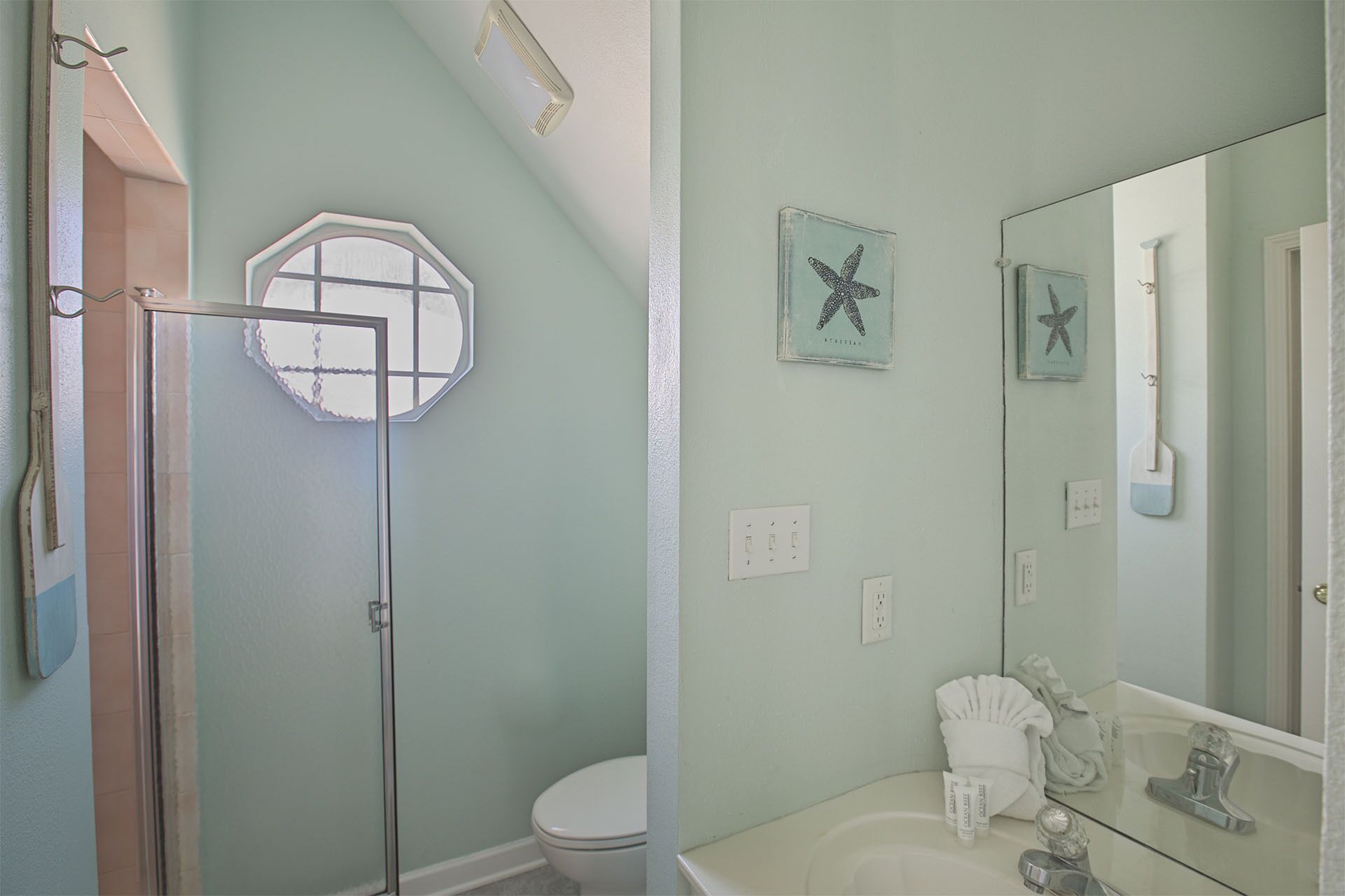 Un bagno con doccia, toilette e lavandino. Sono presenti decorazioni a forma di stella marina sulle pareti.