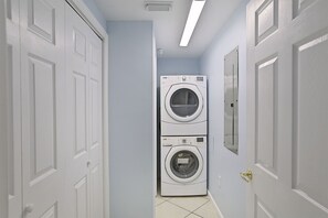 A laundry room with two stacked washing machines, white doors, and a ceiling light.