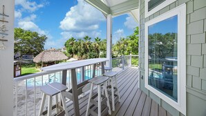 A covered outdoor area with a pool, bar stools, and a view of a tropical landscape. - Hideout – Updated! Pet Friendly & Walk to Beach! (Destin)