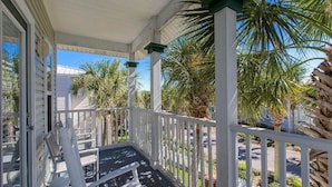 A covered porch with white railings and a bench, surrounded by palm trees and a clear blue sky. - All 4 Fun - Gulfside Cottages, Community Pool, Steps to the Beach! (Miramar Beach)