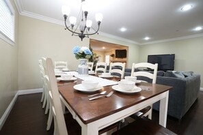 A dining area with a wooden table, white chairs, and a chandelier.