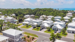 A residential area with multiple two-story houses, a main road, and a view of the ocean in the background. - Gone Coastal - Dune Allen Beach! 30A! Community Pool! Steps to the Sand! (Santa Rosa Beach)