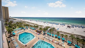Et resort med flere swimmingpools, strandparasoller og havudsigt.