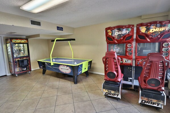 A room with a ping pong table, two arcade machines, and a ventilation system.