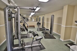 A gym with various exercise equipment, a mirror, and a bench.